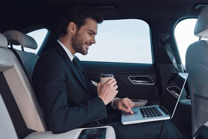 A business passenger working in the back of a DG car